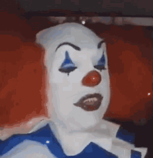 a close up of a clown 's face with red hair and blue eyes .