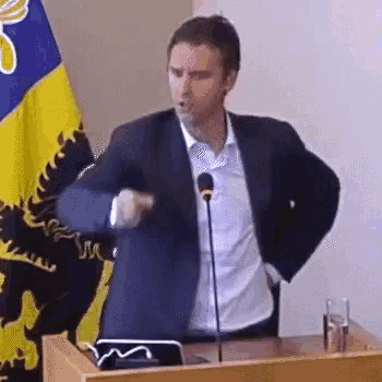 a man in a suit is standing at a podium giving a speech while dancing .