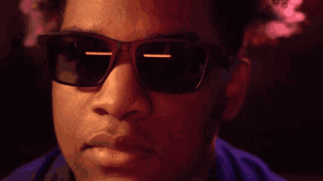 a close up of a man wearing sunglasses and smoking