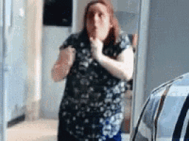 a woman in a floral shirt is standing in front of a mirror .