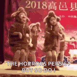 a group of children are dancing on a stage with a sign that says the horrors persist but so do i .