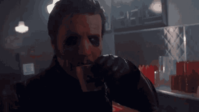 a man with a mask on his face is drinking a cup of coffee .