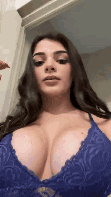 a woman is wearing a blue lace bra and looking at the camera .