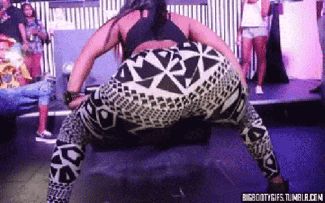 a woman is doing a butt flip on a stage in front of a crowd of people .