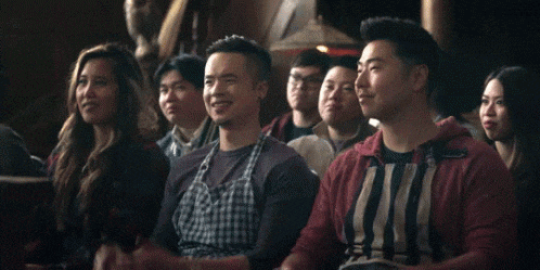 a group of people are sitting in a dark room and applauding