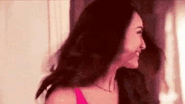 the woman is wearing a pink bra and smiling .