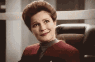 a woman in a red jacket is sitting in a chair smiling .