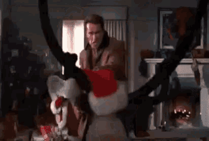a man in a santa hat is standing in a living room next to a reindeer .
