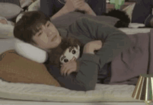 a man is laying on a bed with a stuffed animal on his shoulder .