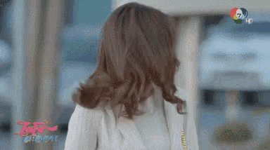 a woman in a white jacket is walking down a street in front of a sign that says ' 7 hd ' on it
