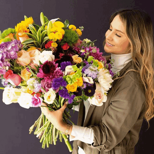 a woman holding a large bouquet of flowers in her hands