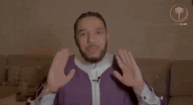 a man with a beard is wearing a purple jacket and white shirt