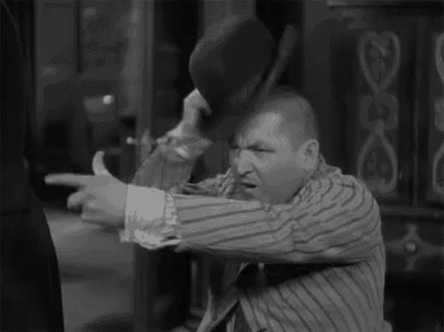 a man in a striped shirt is holding a bowler hat on his head and making a funny face .