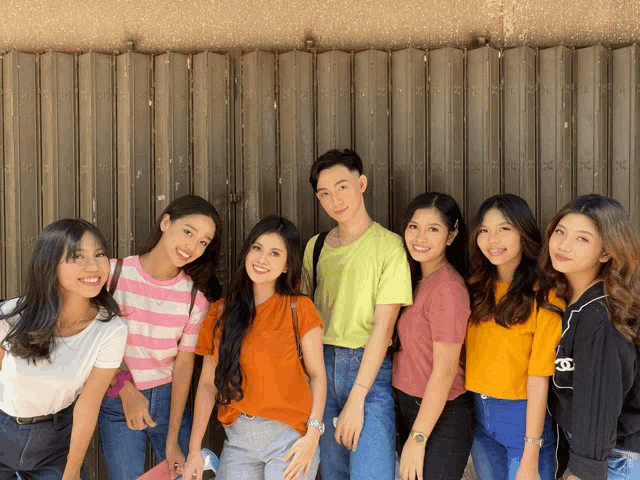 a group of young people posing for a picture with one wearing a yellow shirt that says chanel
