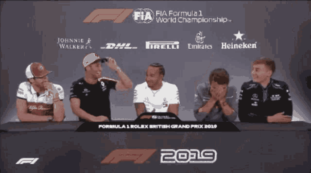 a group of men are sitting at a table with a sign that says formula 1 world championship 2019