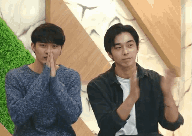 two men sitting next to each other with their hands folded