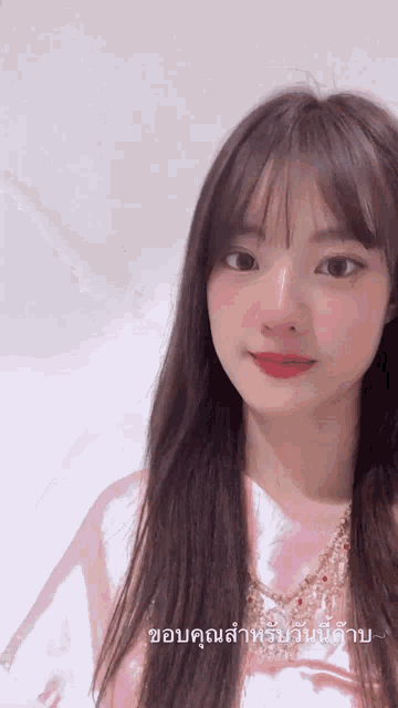 a girl in a pink shirt is looking at the camera with a caption in thai