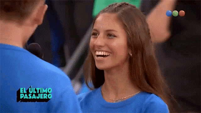 a woman is smiling in front of a sign that says el ultimo pasajero