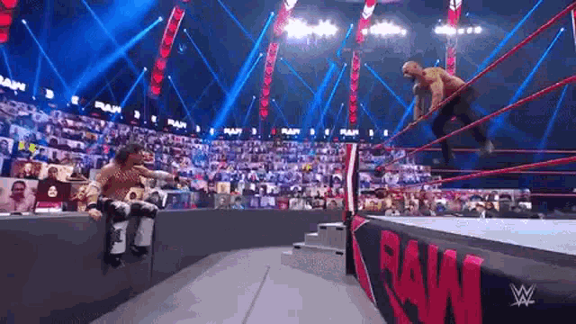 a wrestling match is taking place in a stadium with a crowd watching .