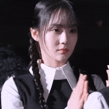 a girl with pigtails is wearing a white shirt and a black vest .