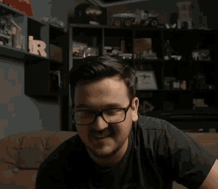 a man wearing glasses and a black shirt is sitting on a couch with the word stevasztok behind him