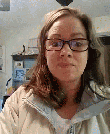 a woman wearing glasses and a jacket is making a face