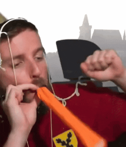 a man wearing headphones and a red shirt with a ferrari logo on it is blowing a balloon