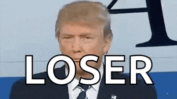 donald trump is wearing a suit and tie and is standing in front of a sign that says loser .