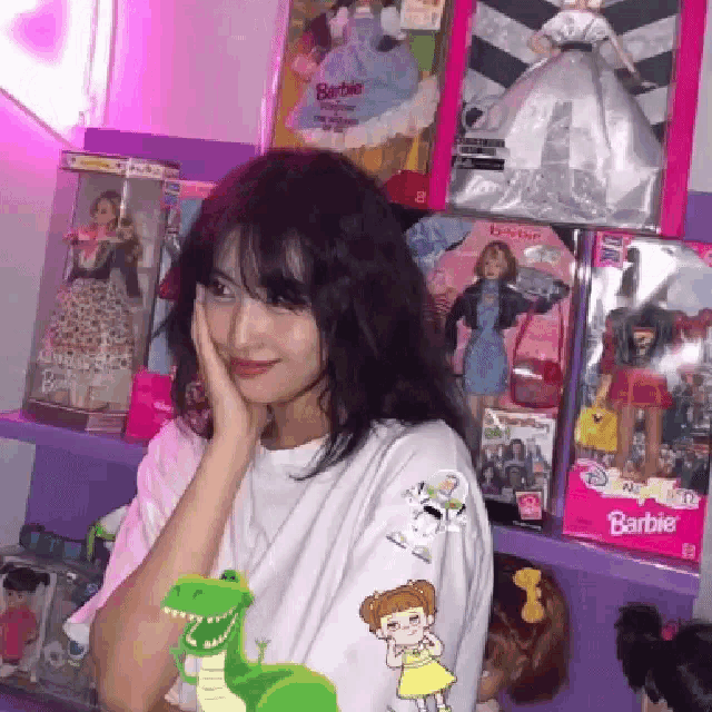 a girl is standing in front of a shelf full of barbie dolls and toys .