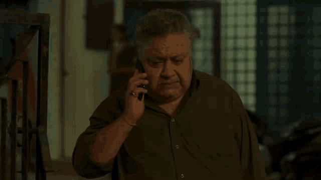 a man in a green shirt is talking on his cell phone
