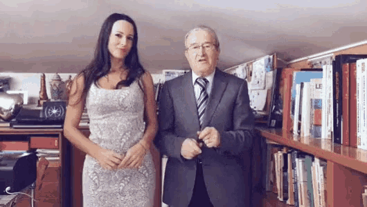 a woman in a white dress stands next to a man in a suit