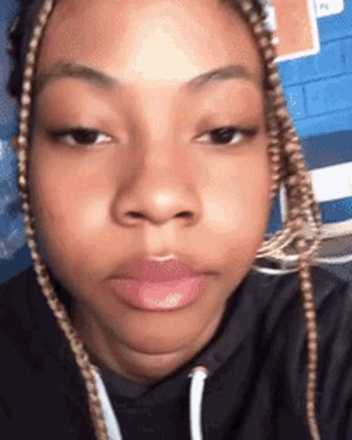 a close up of a woman 's face with braids and pink lips
