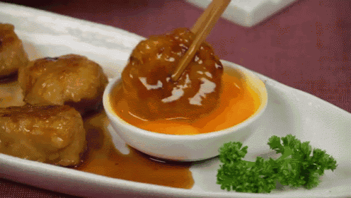a plate of food with a bowl of sauce and chopsticks