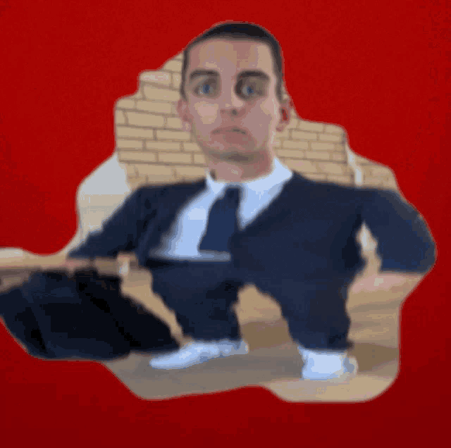 a man in a suit and tie is sitting on the floor with his legs crossed