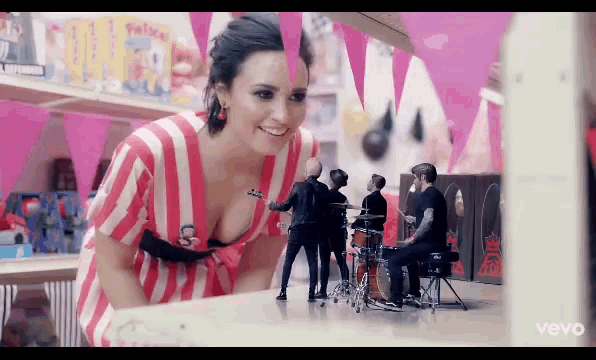 a woman in a red and white striped dress is looking at a band
