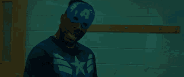 a man wearing a mask with the letter a on it stands in a classroom