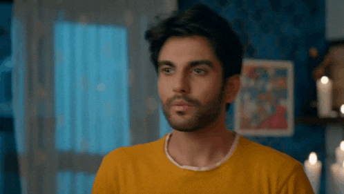a man wearing a yellow sweater is looking at the camera