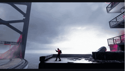 a man in a red jacket is standing on a platform in front of a body of water