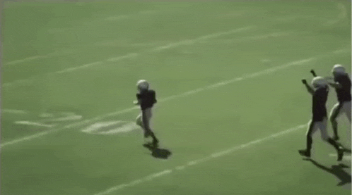 a group of football players are playing on a field and one of them is laying on the ground .
