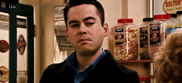a man is standing in front of a shelf with jars of candy and a sign that says bolton 's