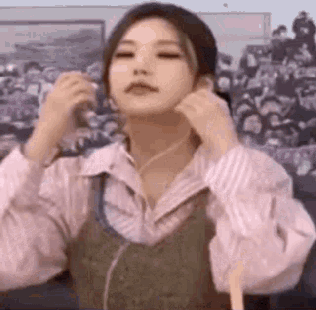 a woman is wearing headphones and adjusting her earring while standing in front of a crowd .