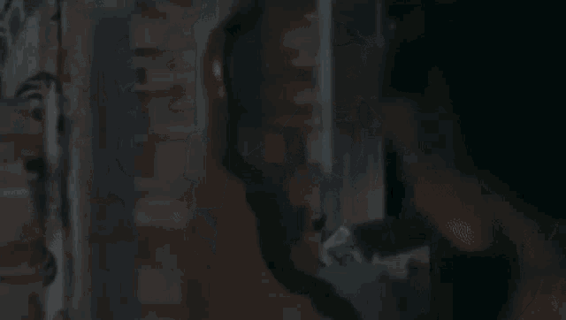 a man in a black jacket is standing in a dark room talking to a woman .