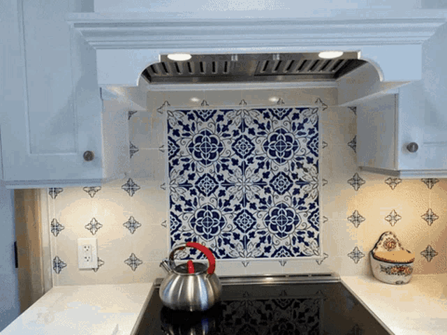 a kitchen with blue and white tiles and a tea kettle on the stove top