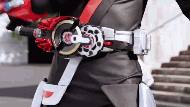 a person wearing a black leather jacket and a belt with a red and white buckle .