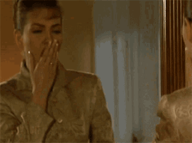 a woman is looking at her face in a mirror and touching her face .
