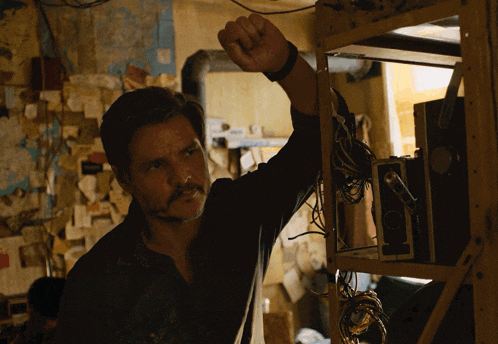 a man with a mustache is leaning on a wooden shelf with a box that says ' a ' on it
