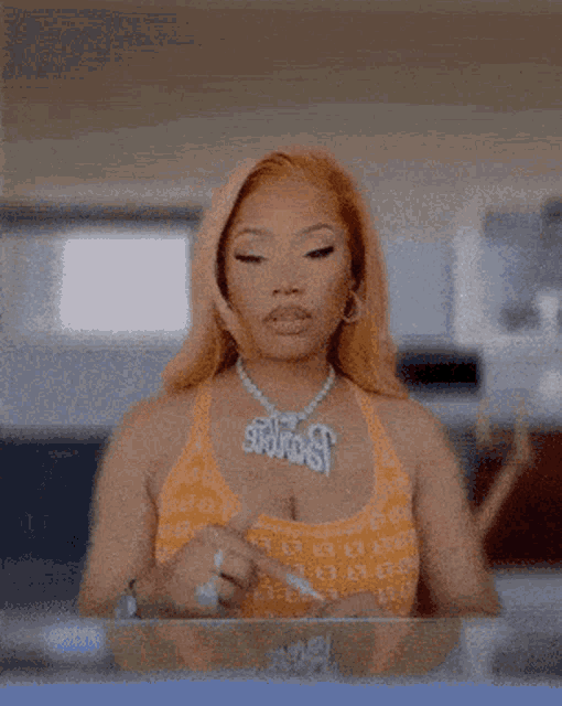 a woman wearing an orange top and a necklace that says ' snoop ' on it