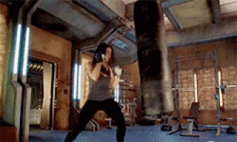 a woman is practicing boxing in a gym with a punching bag .