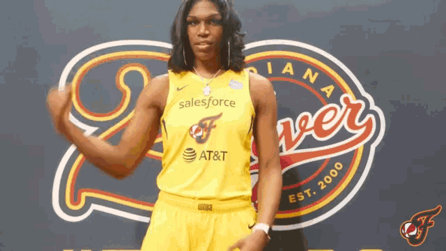 a woman in a yellow salesforce jersey stands in front of a sign