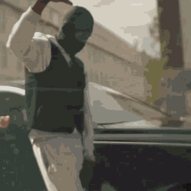 a man wearing a mask and a vest is standing in front of a car